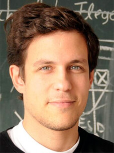 Portrait Ronny Thomale vor Tafel mit physikalischen Formeln, freundlich und offen.